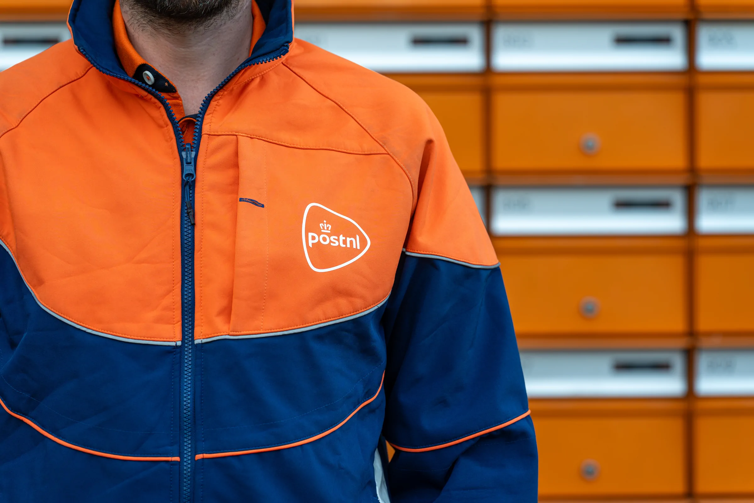 Pakketbezorger in bedrijfskleding voor een rij pakketautomaten